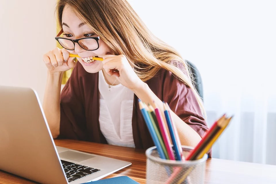 Préparation aux examens de français DELF DALF TCF TEF, étudiante concentrée avec des crayons de couleur et un ordinateur portable